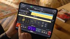 A hand holding an iPad that's running Logic Pro