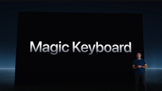 A man standing on a stage with the backdrop announcing the Magic Keyboard in text